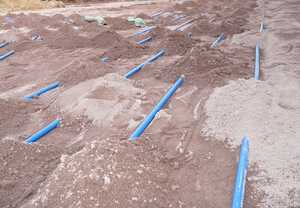 Close up of blue ground source heat pump pipes being covered over with earth